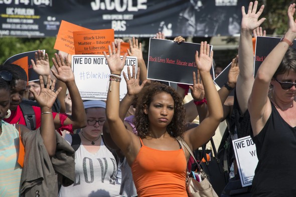 Supporters of Michael Brown raise their hands and hold signs of protest against police brutality