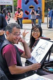 Caricature artist and his subject pose for a photo