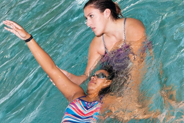 Young woman learning to swim with instructor