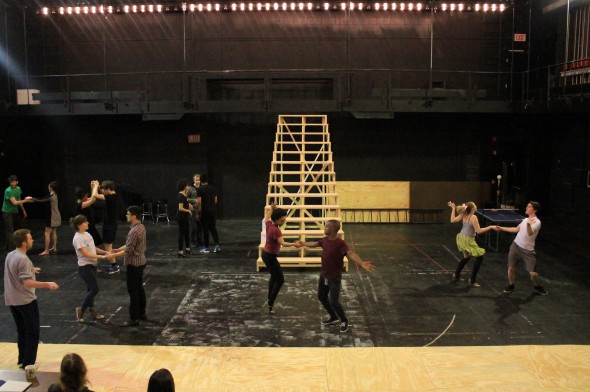 Rehearsing students dance before a "stairway to heaven" under construction.