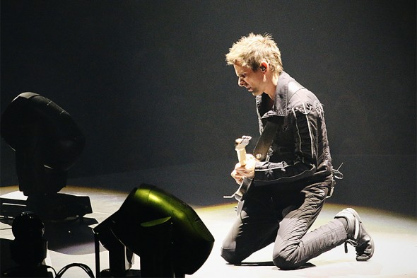Guitarist Matt Belamy kneeling while playing guitar