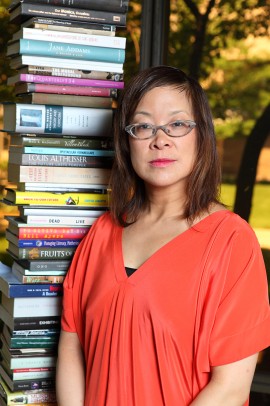 Lisa Lee stands next to a tower of books