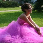 girl sitting in the grass in her prom dress