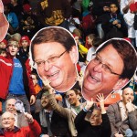 Fans in the crowd hold giant photos of Jerry Bauman's face