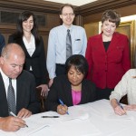 Signing the contract (L-R back row): members of the campus negotiating team, Michael Ginsburg, associate vice chancellor for student affairs, Tonia Nikopoulos, assistant dean, College of Liberal Arts and Sciences, Steven Kregon, executive assistant dean, Graduate College, Marilyn LaBlaiks, assistant director of labor and employee relations, and Liz Sauer, GEO; (front row) Tom Riley, director of labor and employee relations, Chancellor Paula Allen-Meares and Marissa Baker, GEO co-president.