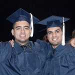 Two graduates hold up their diplomas