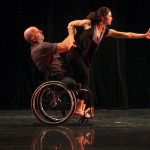 Performer in a wheelchair holds up a woman