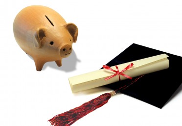 Piggy bank next to a graduation cap and diploma