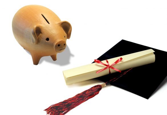 Piggy bank next to a graduation cap and diploma