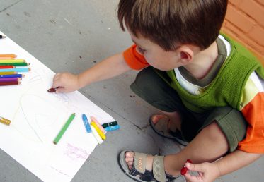 Young boy drawing with crayons