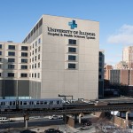 A pink line train passes in front of the UI Hospital