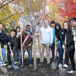 Volunteers pose with shovels around newly-planted tree