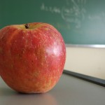 An apple on a desk with a chalkboard in the background