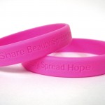 Breast cancer awareness bracelets that read "Share Beauty. Spread Hope."