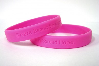 Breast cancer awareness bracelets that read "Share Beauty. Spread Hope."