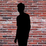 silouhette of a man in front of a brick wall