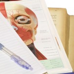notebook and pen on top of anatomy textbook