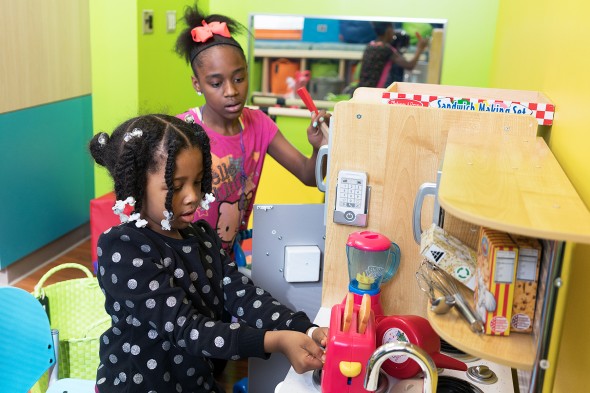 girls playing with a play kitchen