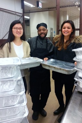 Food Recovery Network members Jullie Han (left) and Jenny Bueno pick up food from UIC Dining Services chef Maurice Hill​