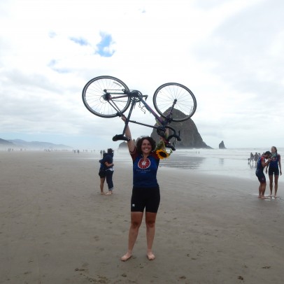 Amanda Koch holding her bike abover her head on a beach