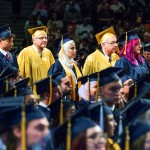 men and women standing in line wearing graduation caps and gowns