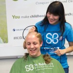 women shaves the head of a man for charity