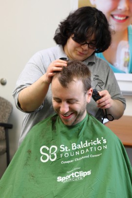 woman shaving the head of a man for St. Baldrick's Foundation