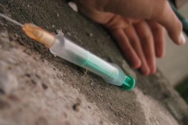 empty syringe on the ground next to a collapsed person
