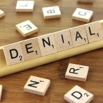 Scrabble tiles spelling out "denial"