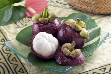 Mangosteen on glass plate with water on fruit.