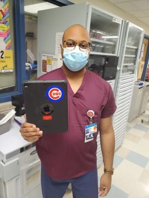 UI Health nurse Asa Cain holds up one of the iPads that Cubs Charities donated to University of Illinois Hospital to allow COVID-19 patients to connect with families over FaceTime.