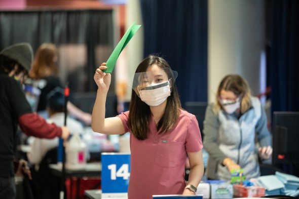 Dentistry student Ellie Park signals she's available to administer another vaccine on Monday, Feb. 1, 2021, at the University of Illinois Chicago Credit Union 1 Arena. (Joshua Clark/University of Illinois Chicago)