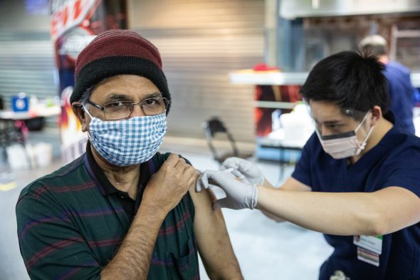 Srinivas Gollapudi smiles under his mask as he receives the COVID-19 vaccine in the Credit Union 1 Arena on Monday, Feb. 1, 2021, at the University of Illinois Chicago. (Joshua Clark/University of Illinois Chicago)