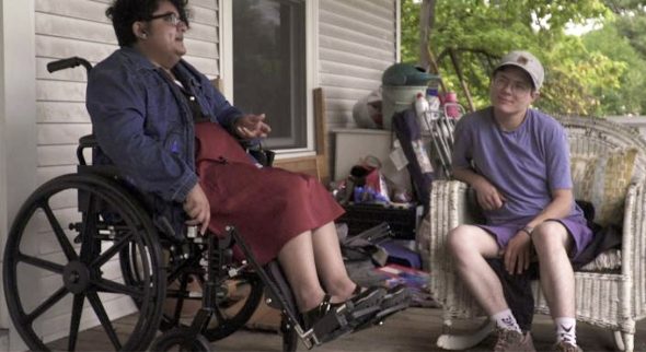 Marrok Sedgwick, right, in a still from his film "People Like Me." Image shows two people, one sitting in a wicker chair and one in a wheelchair, having a conversation.
