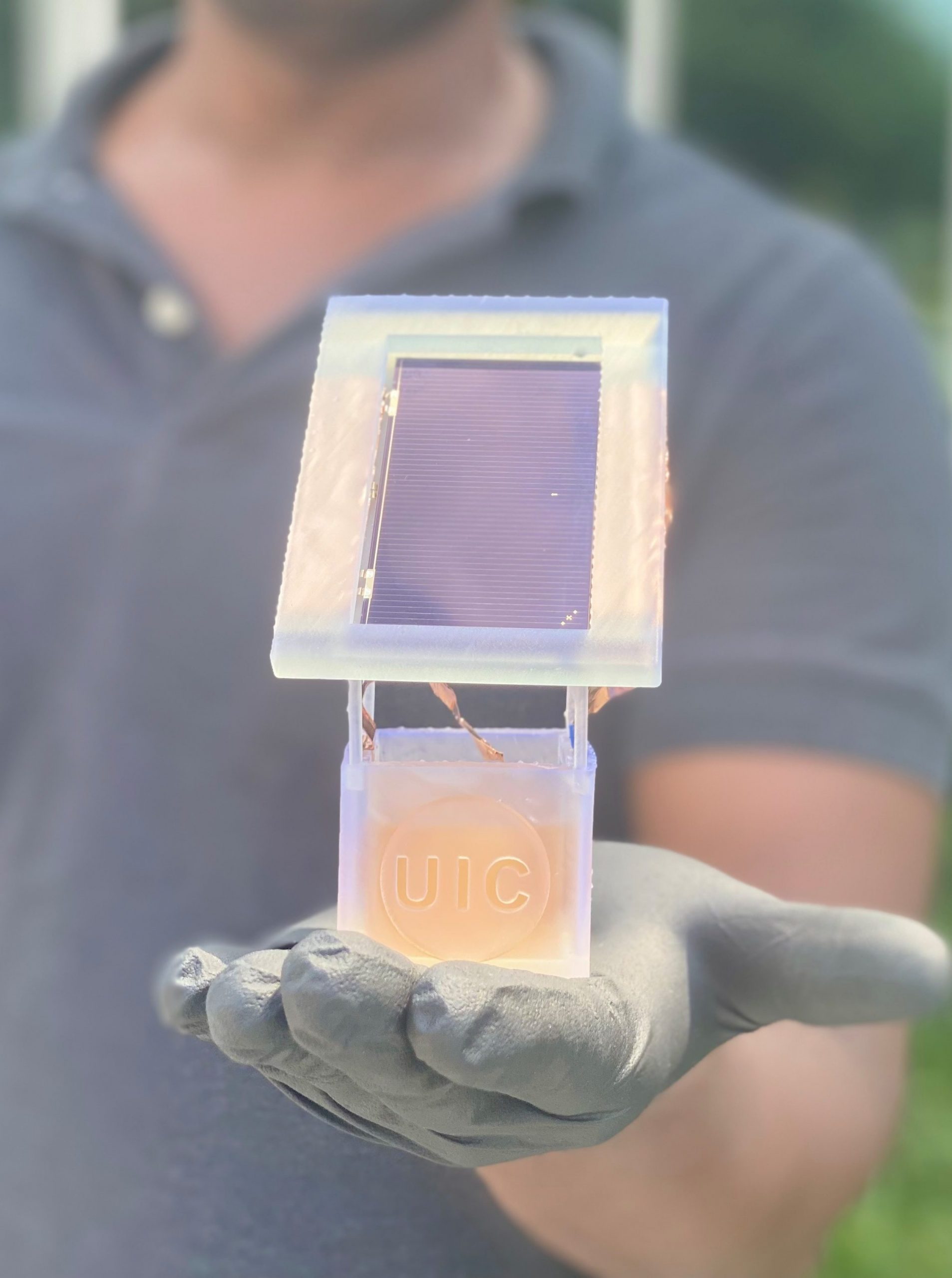 A scientists holds an electrochemical circuit in which a solar cell is attached to a well holding a liquid solution. When charged, nitrates from wastewater in the liquid solution are converted to ammonia.