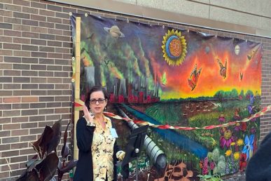 Rosa Cabrera in front of a colorful mural celebrating urban pollinators