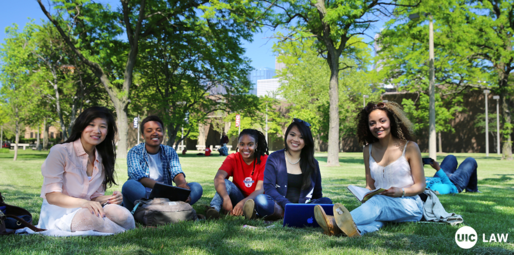 UIC students sitting on grass on campus. UIC Law logo.