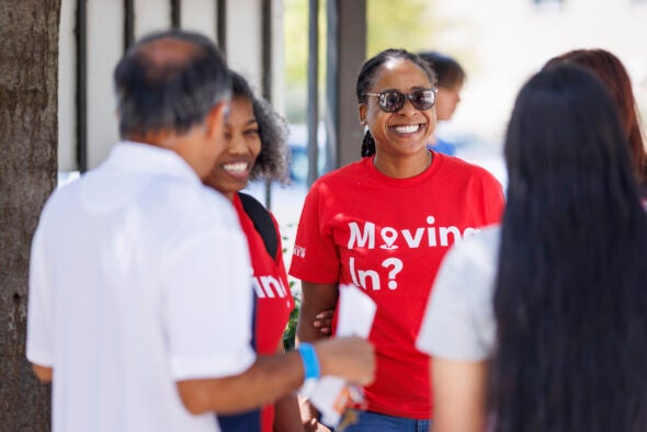 Two volunteers help a parent and a student during move-in day.