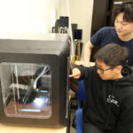 UIC student Chalmers Phua assisted summer camp participant Alexander Wu with 3D printing.