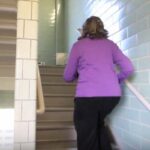 A woman in a purple shirt walks up the stairs.