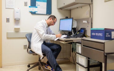 Sam Wainwright sitting in an office desk at UI Health's Outpatient Care Center.