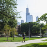 Student riding his skateboard across campus with the Chicago skyline in the background.