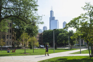 Student riding his skateboard across campus with the Chicago skyline in the background.