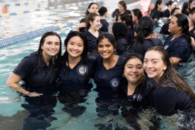 Students pose for a photo after jumping into a pool.