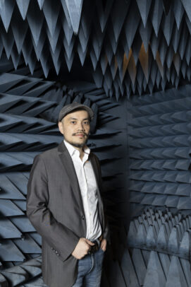 A man posses for a photo with multiple foam pyramids pointing towards him in the background