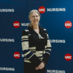 A woman stands in front of a UIC Nursing banner