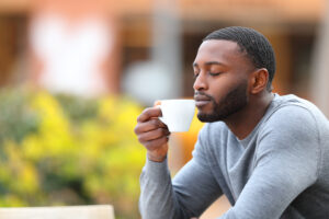 a man smells coffee in a mug he's holding