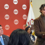 Illinois Gov. JB Pritzker looks on as UIC’s Iván Arenas speaks at a press conference about reducing the racial gap in homelessness in the state.
