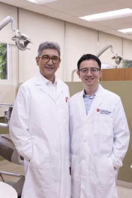 Two men in lab coats stand in a dental clinic.