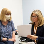 Two women in a medical office look at a piece of paper.